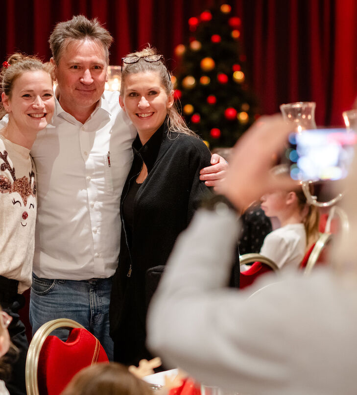 3 adults smile into the camera because they are being photographed