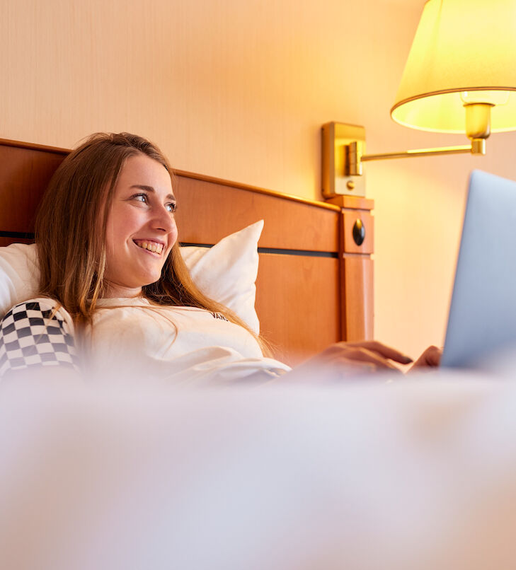 tagungshotel chemnitz - frau in hotelbett mit laptop